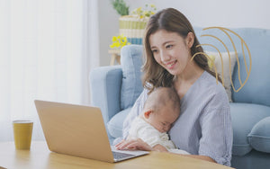 赤ちゃんを抱っこしながら抱っこのオンラインセミナーを受講しているお母さん