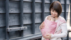 桜柄のベビーラップで首すわり前の赤ちゃんを抱っこする女性