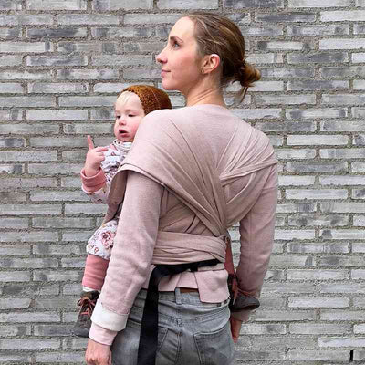 ピンクベージュの抱っこ紐で赤ちゃんを抱っこする女性の後ろ姿