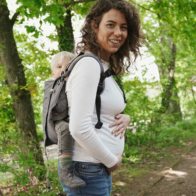 グレーのおんぶ紐で子供をおんぶする妊婦さん
