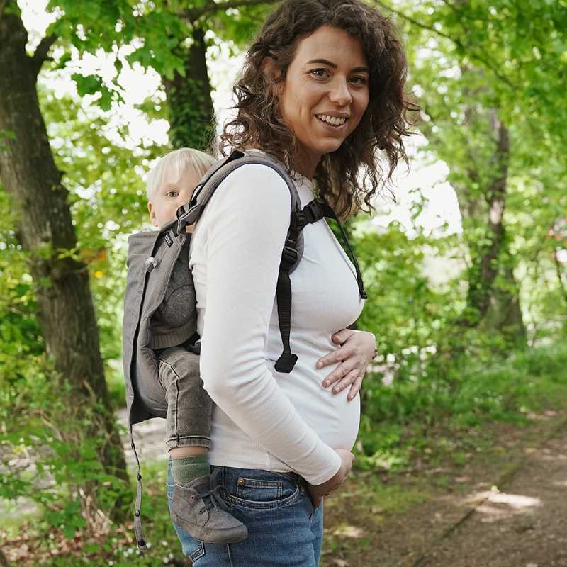 グレーのおんぶ紐で子供をおんぶする妊婦さん