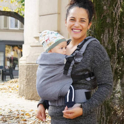 帽子をかぶった赤ちゃんを抱っこ紐で抱っこして微笑んでいる女性