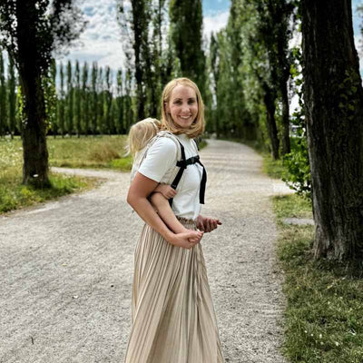 ベージュのおんぶ紐でこどもをおんぶする女性の横からの姿