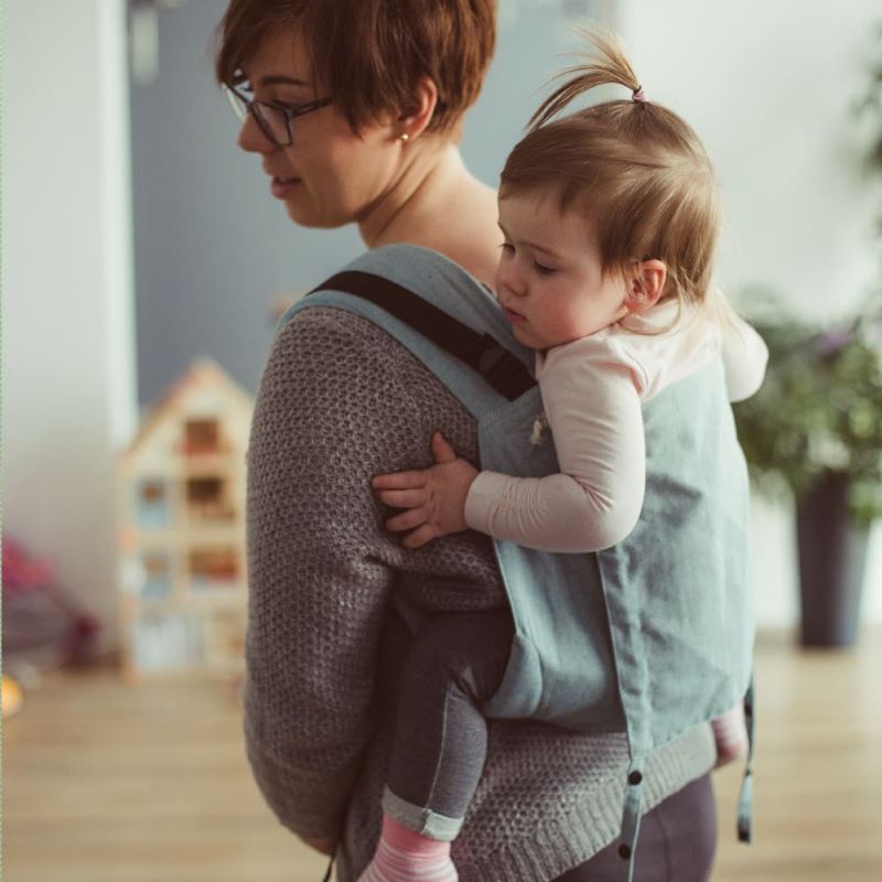 水色のおんぶおんぶ紐で子供をおんぶする女性