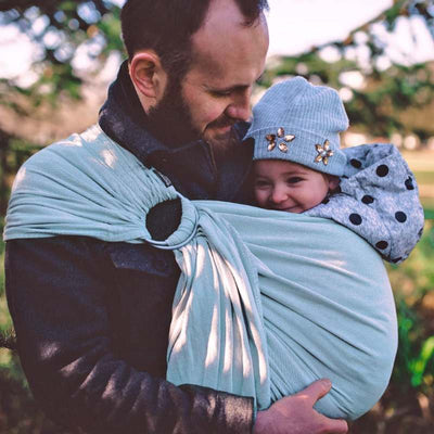 水色のスリングで赤ちゃんを抱っこしてほほ笑む男性