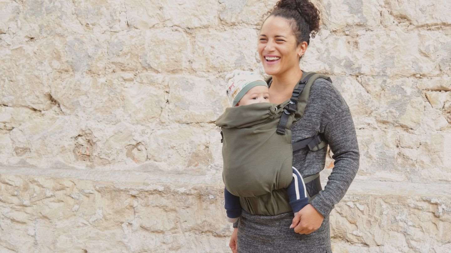 オリーブ色の抱っこ紐で生後5か月の赤ちゃんを抱っこするママ