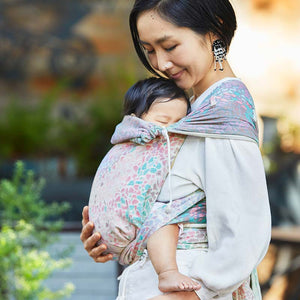 赤ちゃんを布製抱っこ紐で抱っこする女性