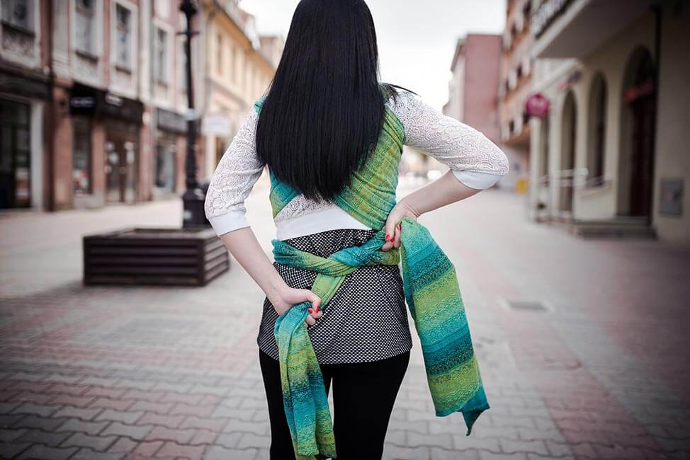 緑色のベビーラップを結ぶ黒髪の女性