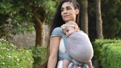 ピンクとグレーのベビーラップで赤ちゃんを抱っこする女性