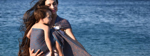 2歳の子どもをスリングで抱きながら海辺を散歩する美人ママ