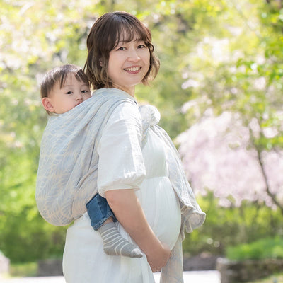 淡いブルーパステル調のベビーラップで2歳をおんぶする妊婦さん