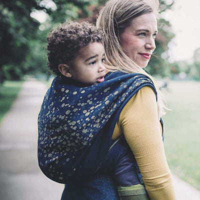 ネイビーにゴールドのドット柄のベビーラップで子供をおんぶする女性