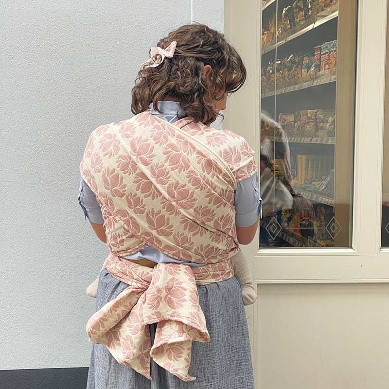 ローズピンクの蓮柄のベビーラップで赤ちゃんを抱っこする女性の後ろ姿