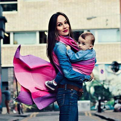 ピンクのストライプベビーラップで子供を抱くデニムをはいた女性