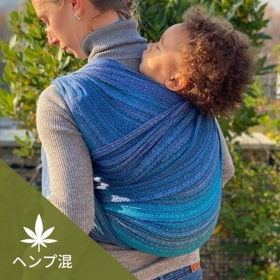 青いヘンプ混のベビーラップで子どもを高くおんぶする女性