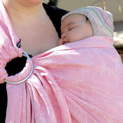 桜デザインのピンク色のスリングで抱っこされながらスヤスヤ眠る赤ちゃん