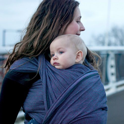 赤ちゃんをベビーラップで縦抱きにしたロングヘアの女性
