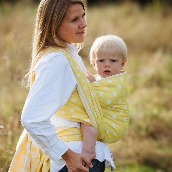 黄色のベビーラップで抱っこされて散歩する親子