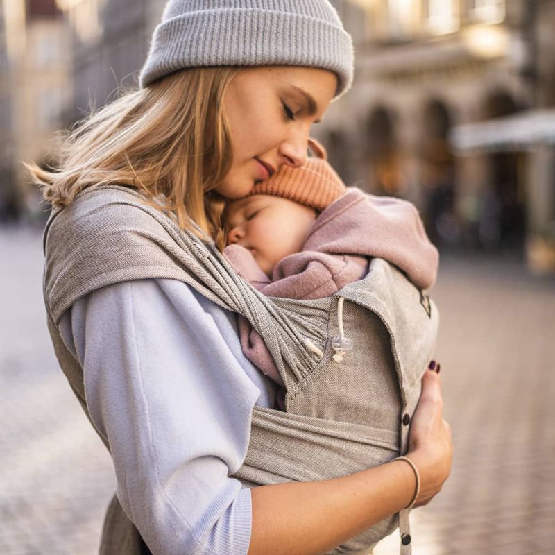 グレーの抱っこ紐で眠る赤ちゃんを抱っこする女性