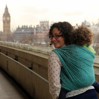 ロンドンでグリーンのベビーラップで子供を背負う女性