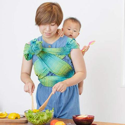 料理しながら抱っこ紐で赤ちゃんをおんぶするお母さん