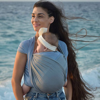 水色とグレーの抱っこ紐で赤ちゃんを抱っこする女性