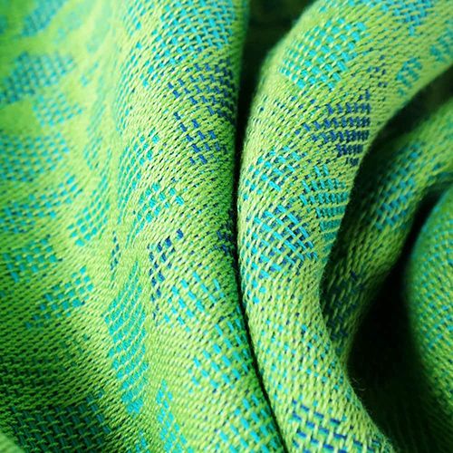 緑の布地に水色と青の糸でモザイク柄を描いている布地