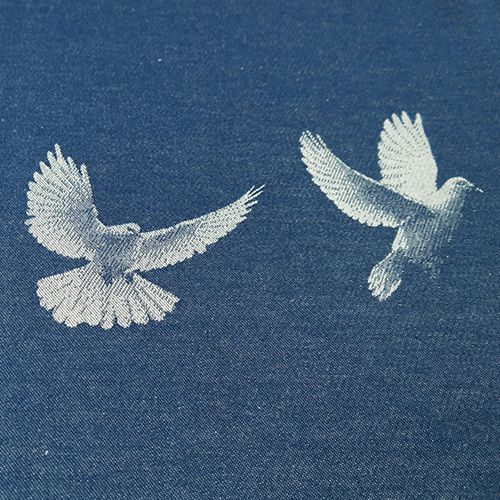 青地に白い鳩が二羽飛ぶ様子が描かれている布地