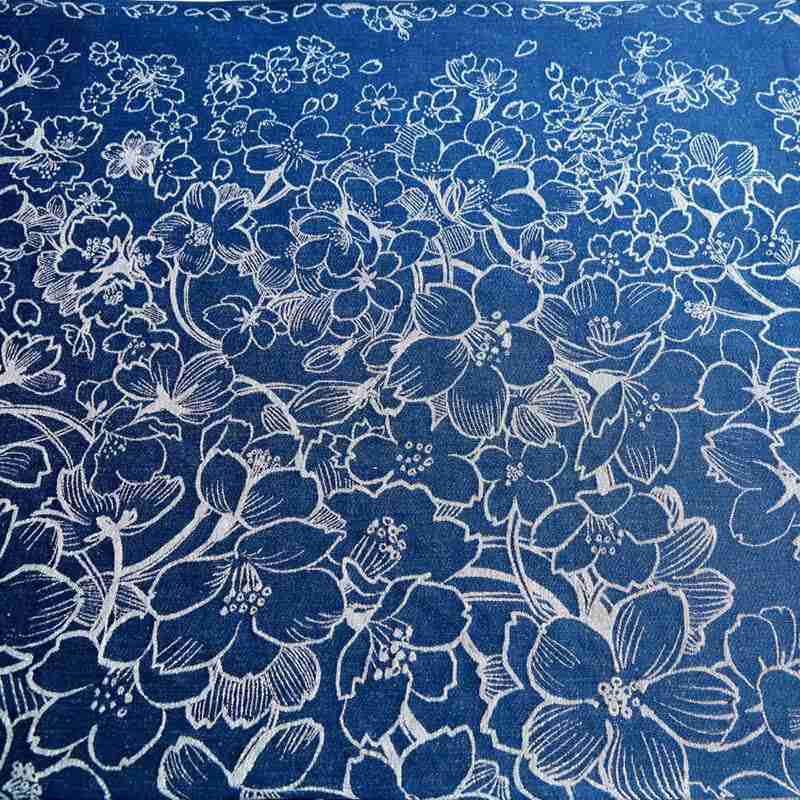 白い桜が風に舞う様子が一面に描かれたブルーの布地