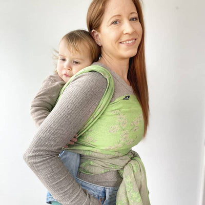 グリーンのベビーラップで赤ちゃんをおんぶしている欧米の女性
