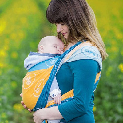 黄色とブルーの抱っこ紐で赤ちゃんを抱く女性
